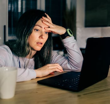 Woman holding her head upset looking at laptop