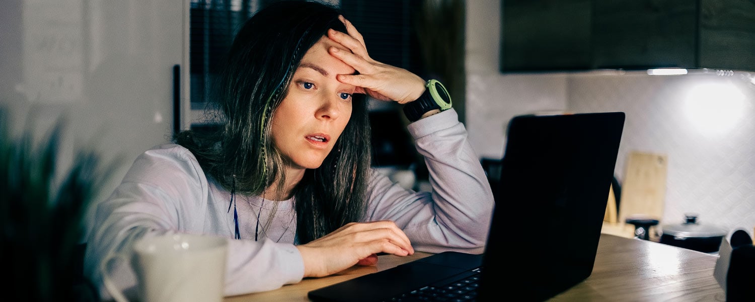 Woman holding her head upset looking at laptop