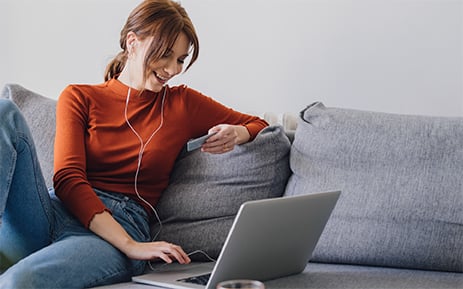 Woman looking at credit card and using laptop