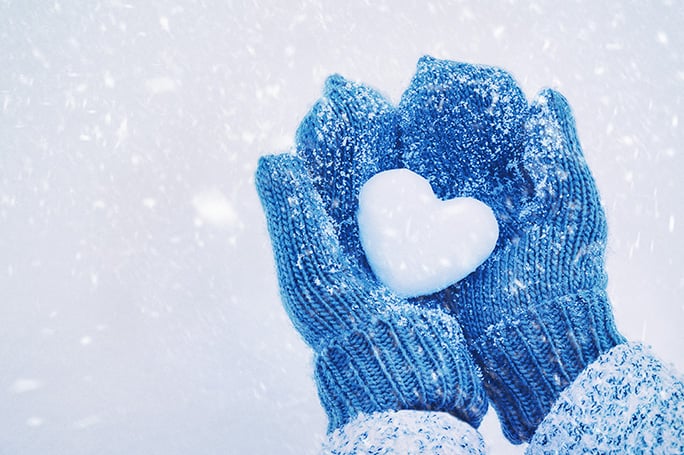 Blue Mittens holding heart shaped snow