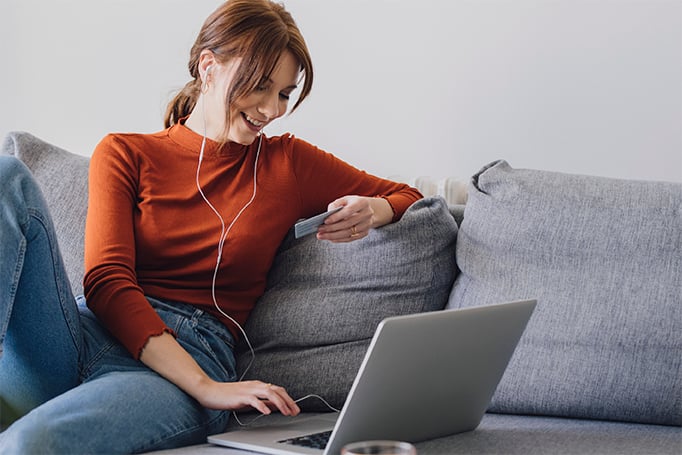 Woman looking at credit card and using laptop