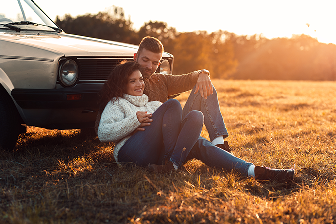 Man and woman leaning against their car