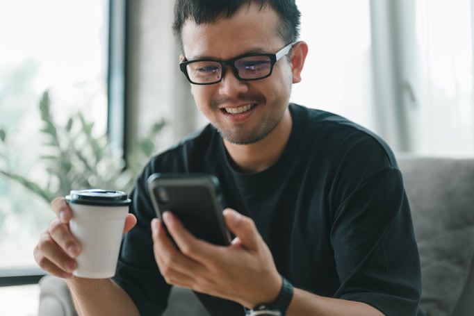 Man holding phone and cup of coffee