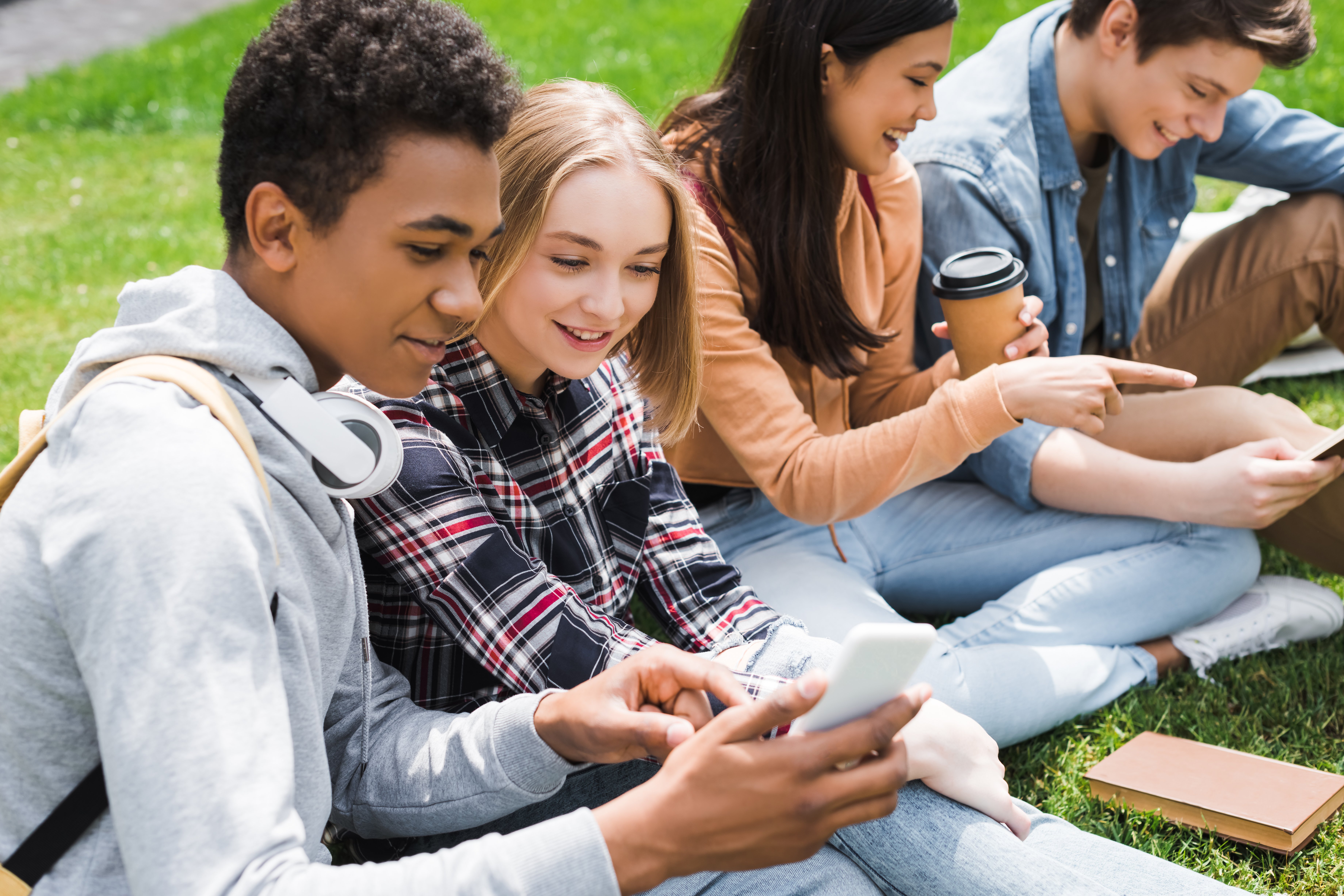 Kids sitting the grass looking at phone