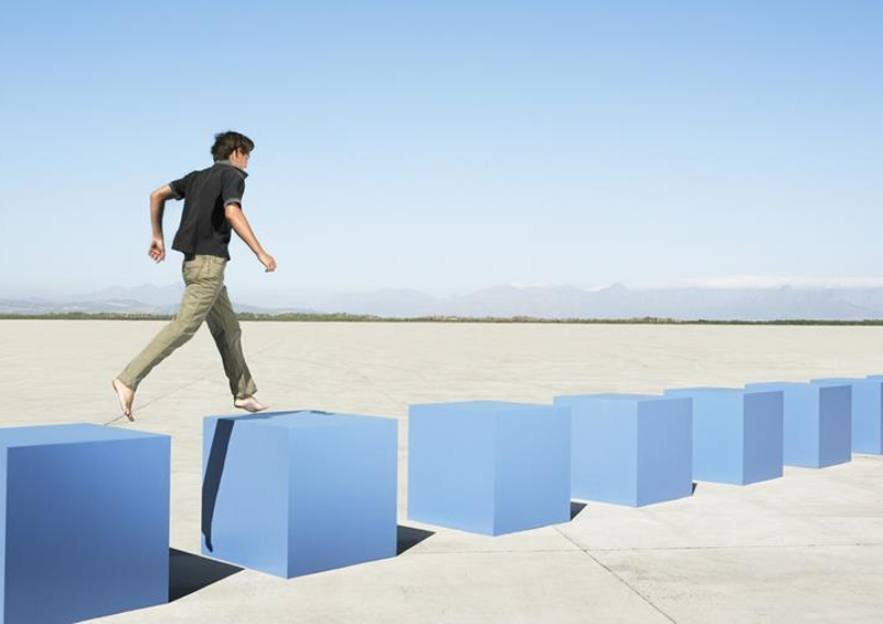 Man walking carefully on giant blocks